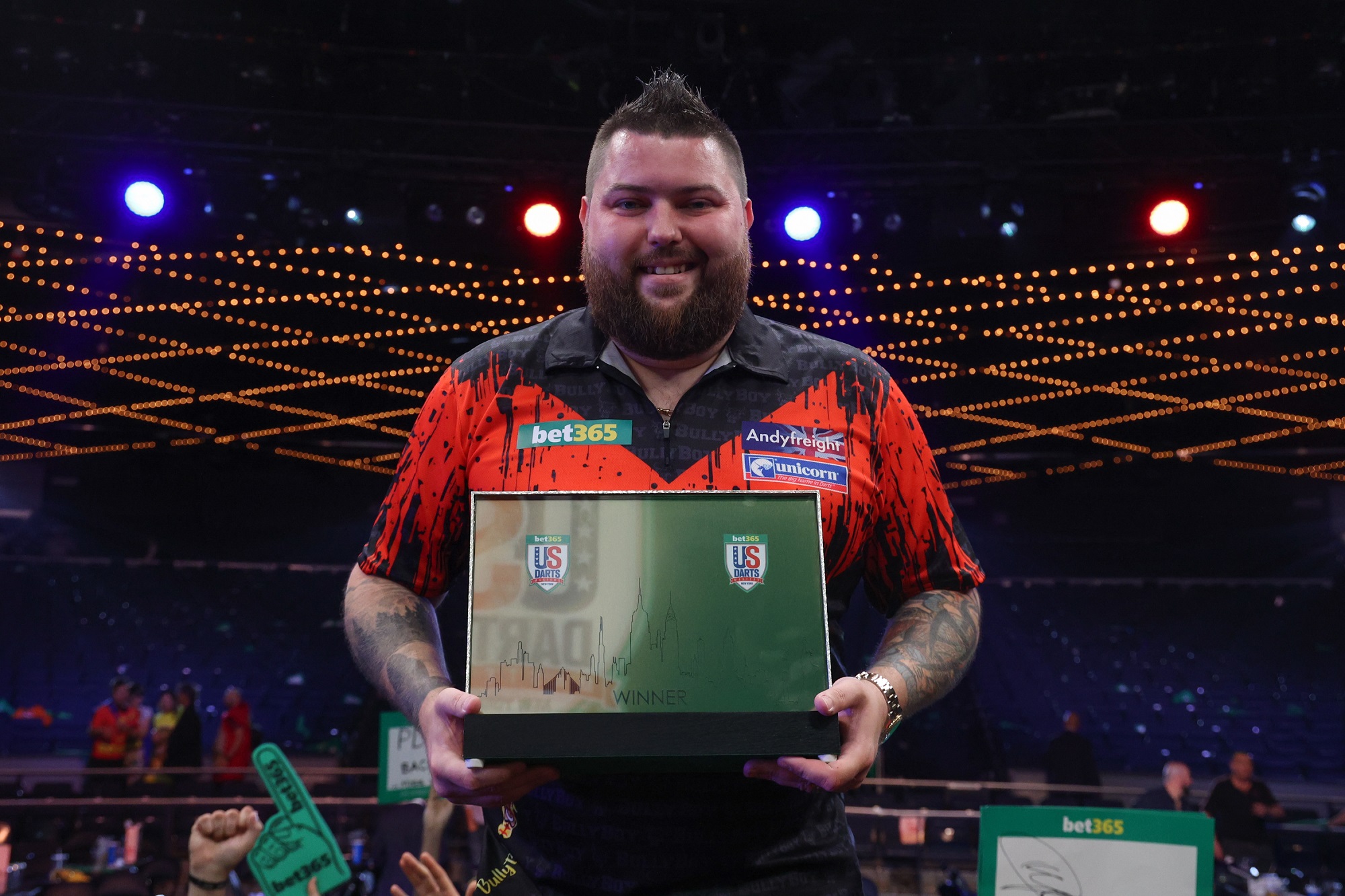Michael Smith poses with the bet365 US Darts Masters title on stage at Madison Square Garden